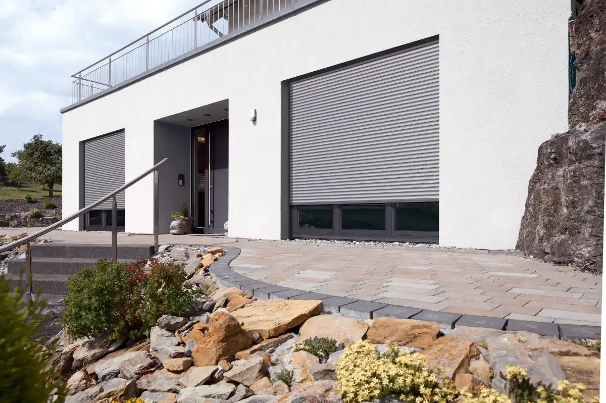 Elegante Hausansicht mit Rollläden und Steingarten Moderne Hausfassade mit geschlossenen Rollläden und Steingarten